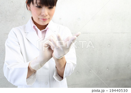 ゴム手袋をはめる白衣の女性の写真素材