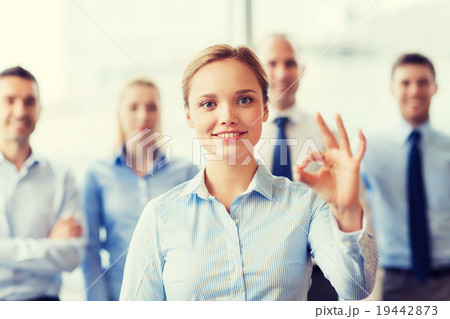 smiling businesswoman showing ok sign in office 19442873