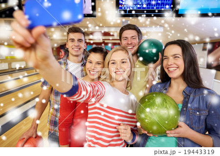 happy friends with smartphone in bowling club 19443319