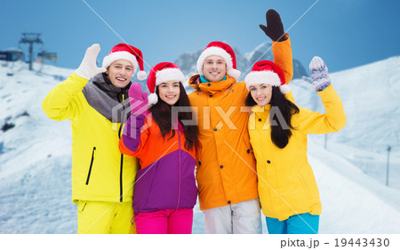 happy friends in santa hats and ski suits outdoors 19443430