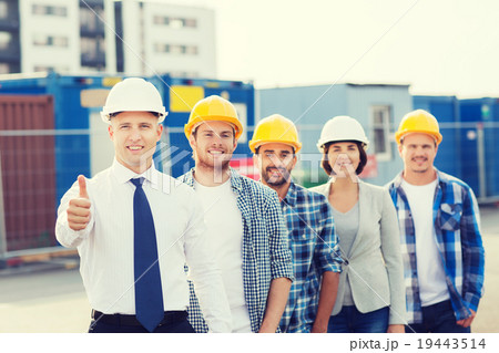 group of smiling builders in hardhats outdoors group of smiling builders in hardhats outdoors 19443514