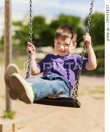 happy little boy swinging on swing at playground 19443837