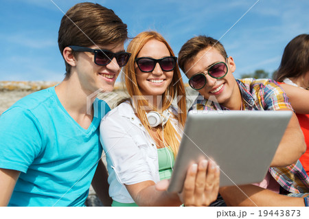 group of smiling friends with tablet pc outdoors 19443873