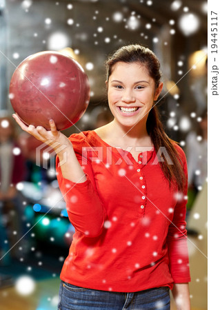 happy young woman holding ball in bowling club 19445117