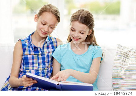 two happy girls reading book at home 19445374