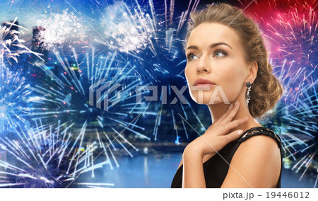 beautiful woman wearing earrings over firework 19446012