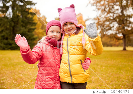 two happy little girls waving hand in autumn park two happy little girls waving hand in autumn park 19446475