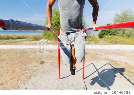 young man exercising on parallel bars outdoors 19446588