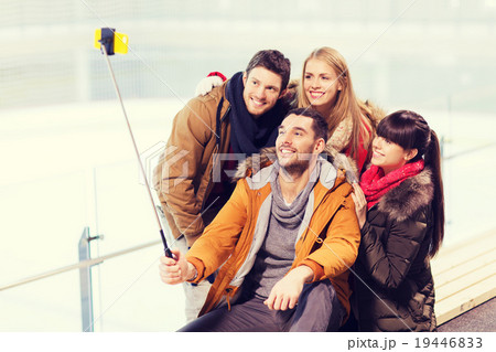 happy friends with smartphone on skating rink 19446833