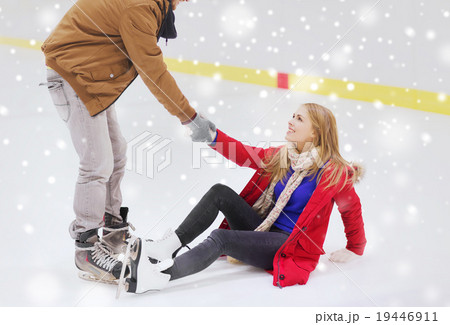 man helping women to rise up on skating rink 19446911