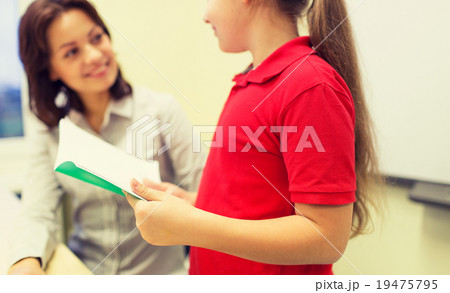 school girl with notebook and teacher in classroom 19475795