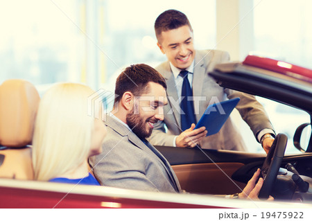happy couple with car dealer in auto show or salon 19475922