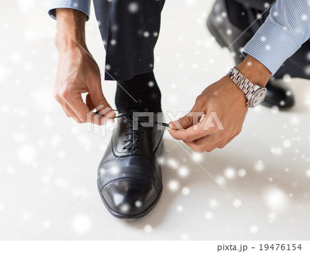close up of man leg and hands tying shoe laces close up of man leg and hands tying shoe laces 19476154