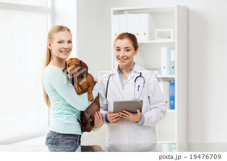 happy woman with dog and doctor at vet clinic happy woman with dog and doctor at vet clinic 19476709
