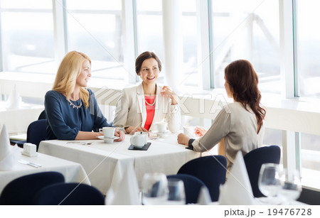 women drinking coffee and talking at restaurant women drinking coffee and talking at restaurant 19476728