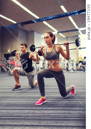 young man and woman training with barbell in gym young man and woman training with barbell in gym 19477150