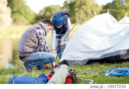 happy father and son setting up tent outdoors 19477234