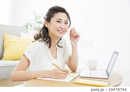 パソコンを見ながらメモする若い女性 19478794