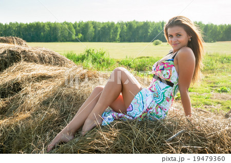 Young blond woman sits on hay 19479360