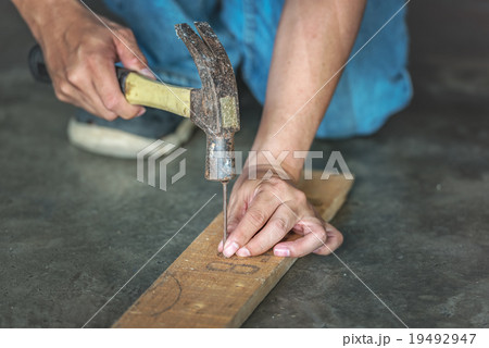 man hands drive nail with a hammer in wooden 19492947
