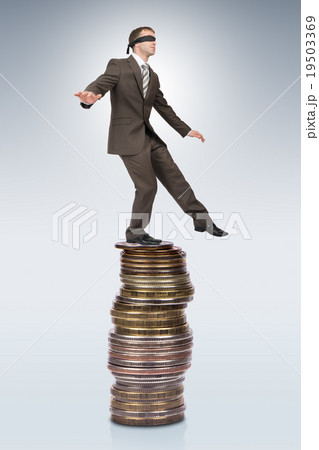Businessman walking from edge of coins pile 19503369
