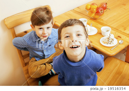 little cute boys eating dessert on wooden kitchen little cute boys eating dessert on wooden kitchen 19516354
