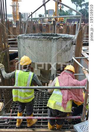 Workers pouring concrete into pile cap formwork Workers pouring concrete into pile cap formwork 19516910