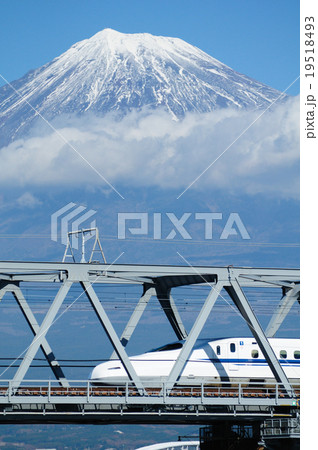 雪を被った富士山をバックに富士川橋梁を渡る新幹線の写真素材