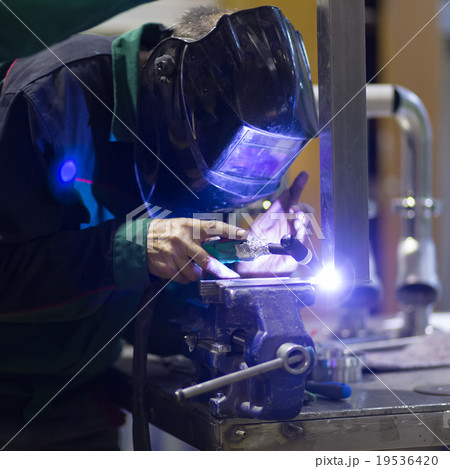 Industrial worker welding in metal factory. 19536420