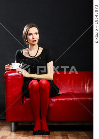 Retro woman holds tea cup sitting on sofa Retro woman holds tea cup sitting on sofa 19543973