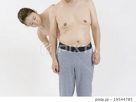 太った男性のお腹の前で怒った顔のスリムな女性の写真素材