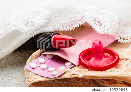 Pills condom and lipstick on lace lingerie 19579848