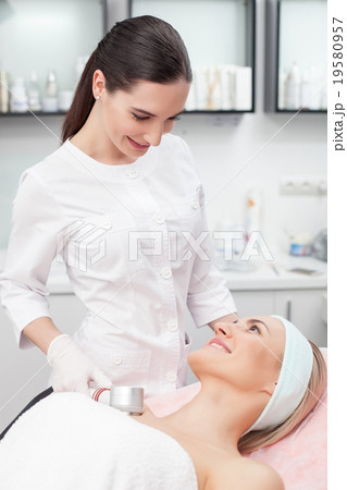 Attractive young beautician is treating her 19580957