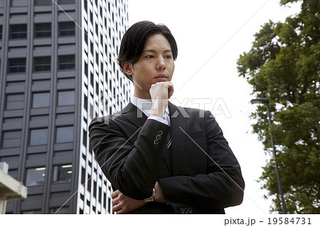 爽やか30代男性スーツ姿のビジネスマン 考えるポーズの写真素材