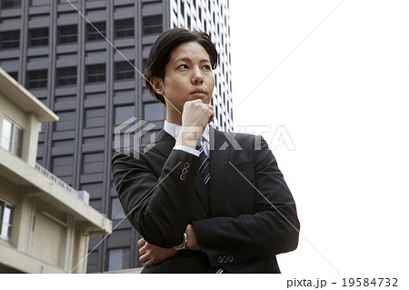 爽やか30代男性スーツ姿のビジネスマン 考えるポーズの写真素材
