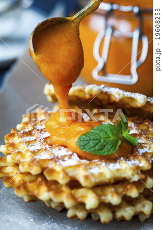 Wafers on baking paper with a jar of persimmon jam Wafers on baking paper with a jar of persimmon jam 19608253