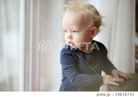 Adorable toddler girl looking through the window 19610735