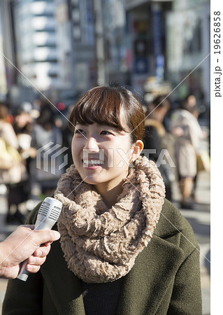 街頭インタビューを受ける若い女性 街中雑踏 東京原宿表参道の写真素材