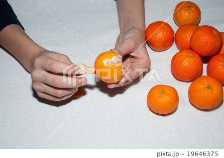 Kid's hands clean tangerine on white table Kid's hands clean tangerine on white table 19646375