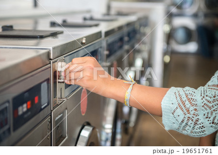 Woman making payment putting quarter to laundromat Woman making payment putting quarter to laundromat 19651761