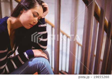 Worried student sitting in hallway 19655260