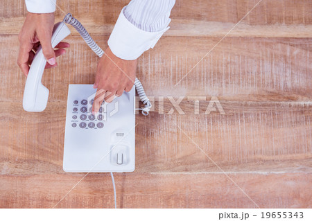 Businesswoman holding a phone at her desk Businesswoman holding a phone at her desk 19655343