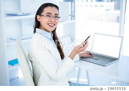 Smiling businesswoman using laptop  19655518