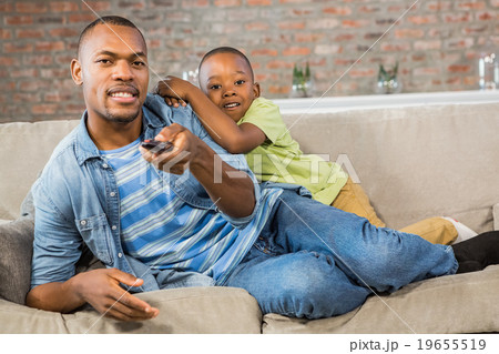 Father and son watching tv together on the couch Father and son watching tv together on the couch 19655519