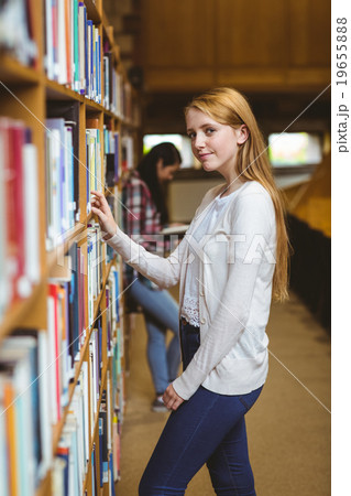 Blond student looking for book in library shelves Blond student looking for book in library shelves 19655888