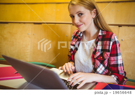 Smiling student using laptop during class Smiling student using laptop during class 19656648