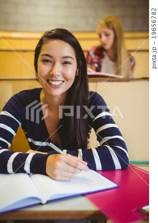 Smiling student writing on notebook Smiling student writing on notebook 19656782