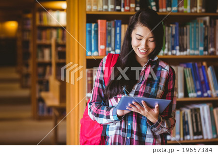 Smiling student in library using tablet 19657384