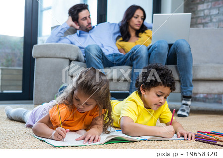 Children laying on the carpet using tablet in living room 19658320