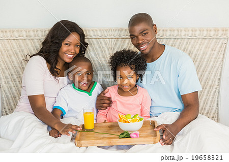 Happy family having breakfast in bed together Happy family having breakfast in bed together 19658321